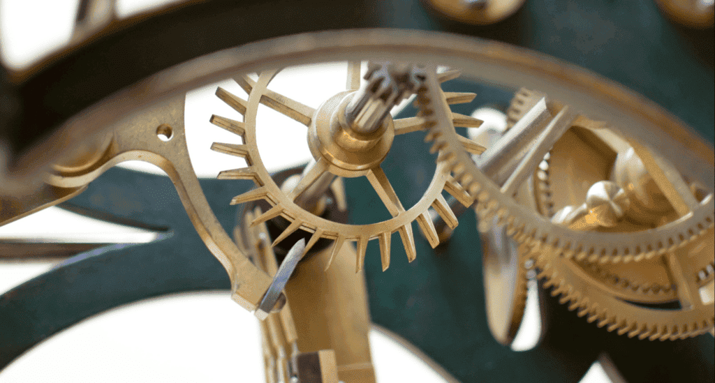 Close-up of interlocking brass gears and mechanical components in a clock mechanism, symbolizing business process systems.