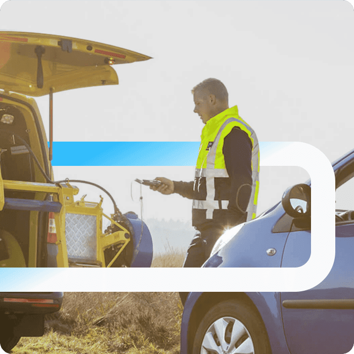 ANWB roadside assistance worker in a high-visibility vest using a diagnostic tool to help a stranded blue car.