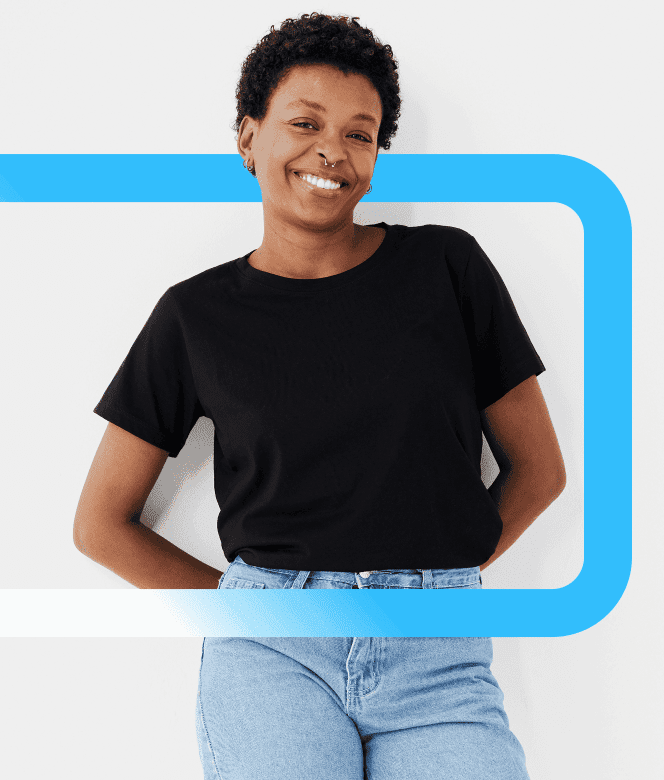 A smiling woman with short curly hair wearing a black t-shirt and blue jeans poses against a light background with a blue
